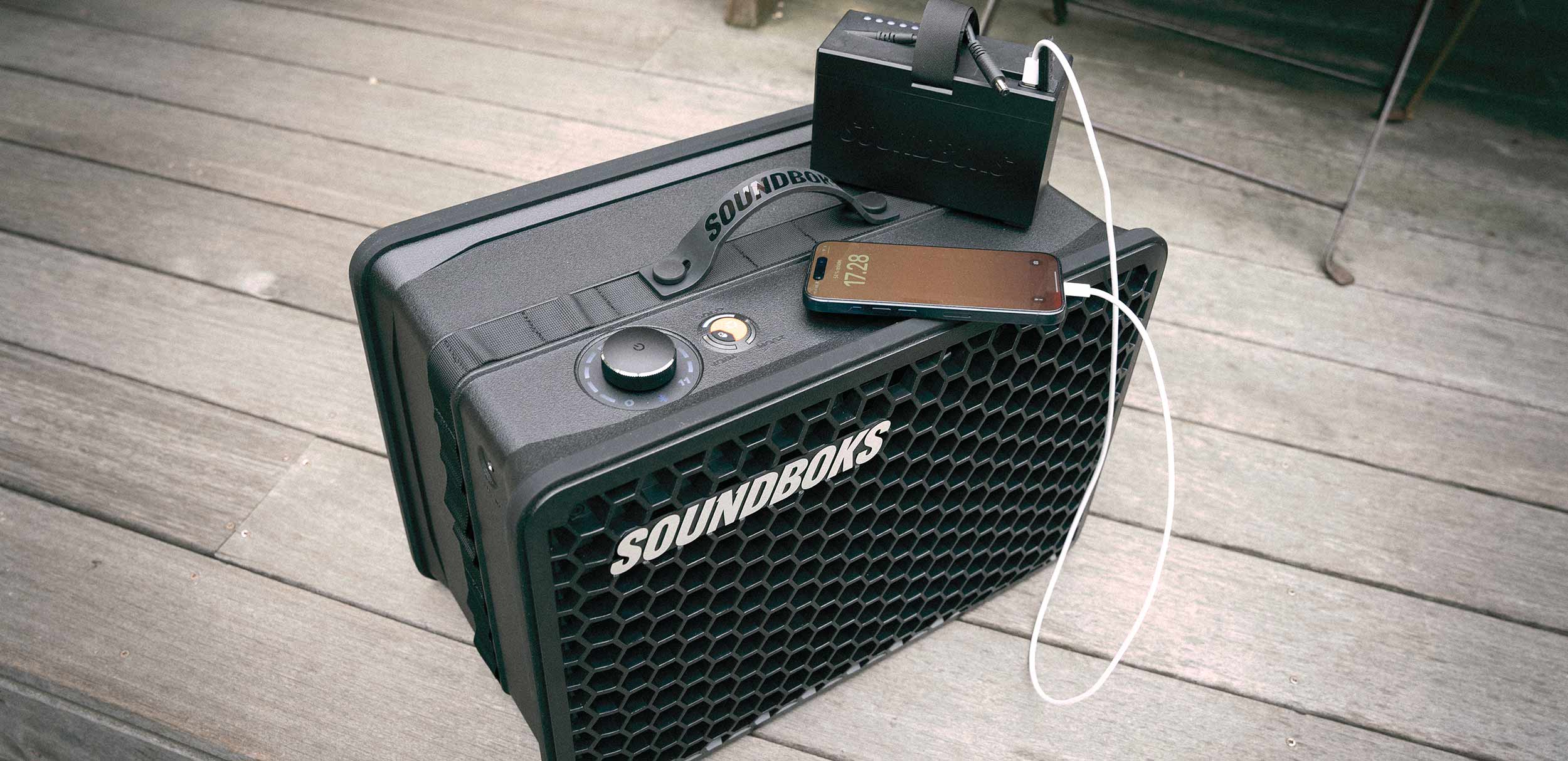 THE BATTERY charging a phone on top of a SOUNDBOKS Go